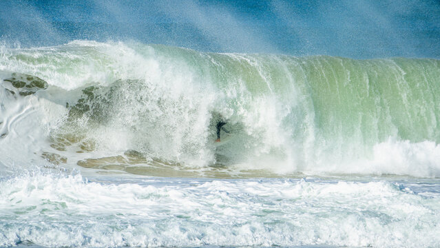 young adult surfing on a big wave in the ocean