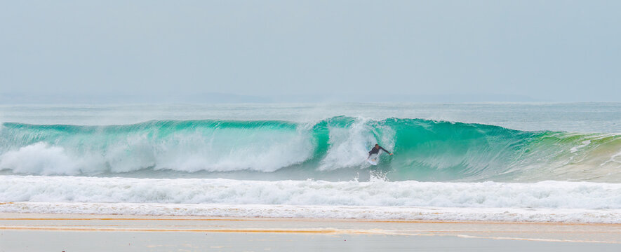 young adult surfing on a big wave in the ocean