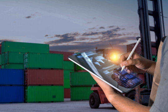Manager using digital tablet for global container shipping and logistics management in cargo yard. Human-created, not AI.
