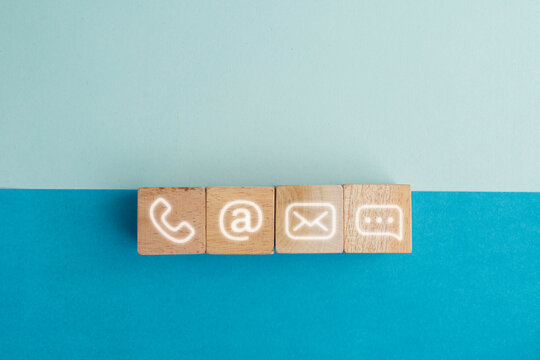 Wooden blocks on table showing phone, email, address and live chat icons. Contact us about customer service center connectivity concept. Internet communication via website