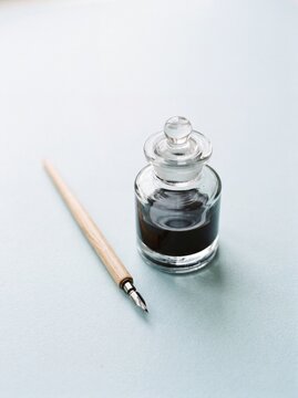 Vintage dip pen and glass inkwell on light surface