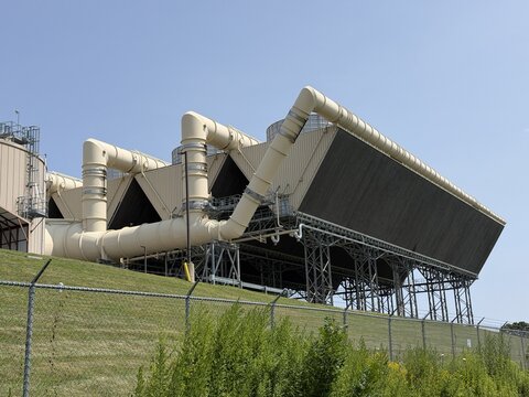 View of the CPV Towantic Energy Center air cooled condenser with large industrial pipes and cooling fans set against a clear blue sky in Oxford, Connecticut, United States.