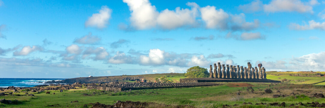 View of the Moais of Ahu Tongariki standing on a stone platform against a blue sky with clouds, overlooking the Pacific Ocean on Easter Island, Valparaiso, Chile.