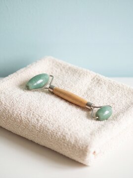 Green jade face roller resting on soft spa towel
