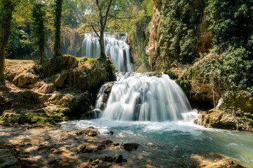 Obraz premium A silky waterfall flows over mossy travertine into an emerald pool in the Monasterio de Piedra natural park in Aragon Spain a serene and refreshing scene of water and lush greenery.
