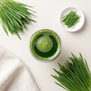 Wheatgrass juice flat lay with fresh cut grass on white background, clean wellness drink still life in top view