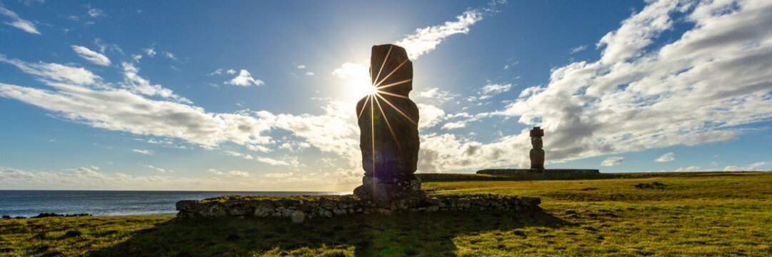 Moais Tahai Archaeological Complex. View of Moai statues standing on the grassy coast with a sunburst effect in the sky, Easter Island, Valparaiso, Chile.