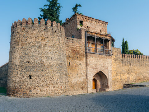 View of the historic Batonis Tsikhe fortress with its stone walls, round tower, and traditional wooden balcony in Telavi, Kakheti, Georgia.
