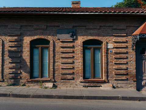 View of a historic brick building with arched windows and a commemorative plaque on the facade in Telavi, Kakheti, Georgia.