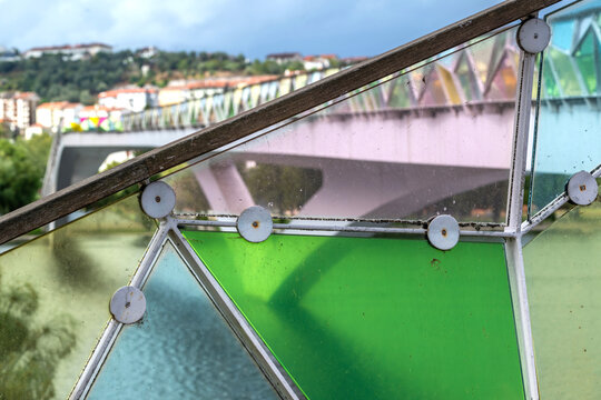 View of Ponte Pedonal Pedro e Ines with its distinctive colorful glass panels and modern architectural design spanning the Mondego River in Coimbra, Coimbra, Portugal.
