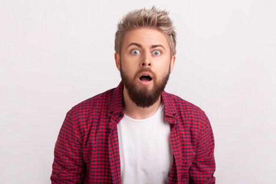 Shocked bearded man with mouth wide open and intense emotional expression showing fear or extreme loud reaction posing isolated over white background