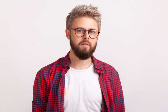 Calm bearded man wearing round glasses with neutral serious facial expression looking directly forward posing isolated over white background