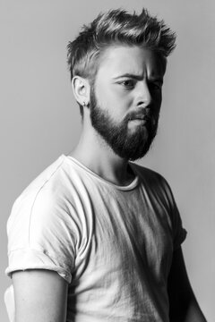 Black and white close up portrait of focused man looking away with serious expression and detailed skin isolated on gray background