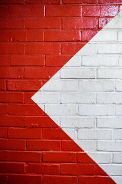 Close Up Of A Bright Red Painted Brick Wall With A Painted White Triangle Offset To The Right With Copy Space