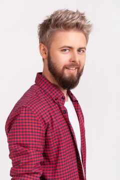 Joyful young man with beard blond dyed hair wearing red checkered shirt laughing happy sincere delight cheerful mood isolated over gray background