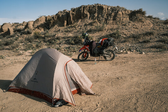 View of a camping tent and a motorcycle parked in the arid landscape near Issyk Kul, Issyk-Kul Region, Kyrgyzstan.