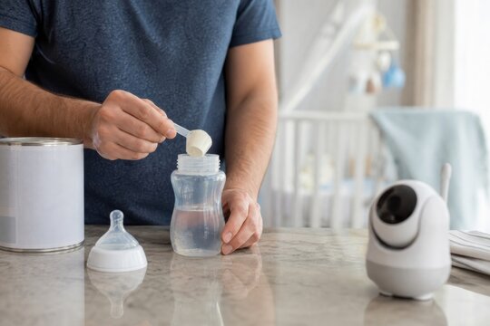 Father preparing a bottle of baby formula in a modern kitchen