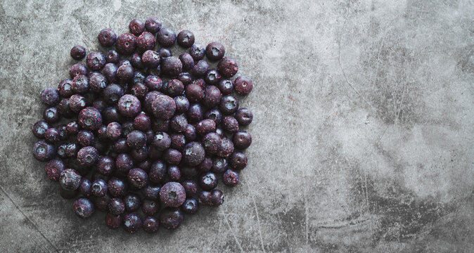 Heap of frozen blueberries on gray background with copy space.