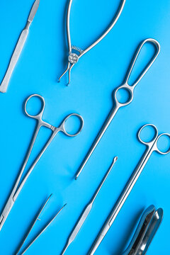 A lot of stainless surgical instruments and tools on blue table, top view. Medical background