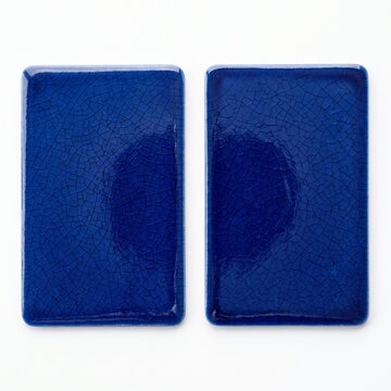 Cobalt blue ceramic tiles with crackle glaze finish, pair of rectangular porcelain samples, glossy blue pottery swatches on white background