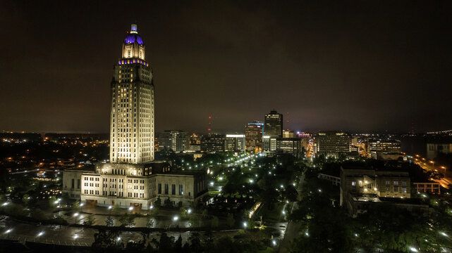Aerial view of the illuminated Louisiana State Capitol building surrounded by the city skyline at night in Baton Rouge, Louisiana, United States.