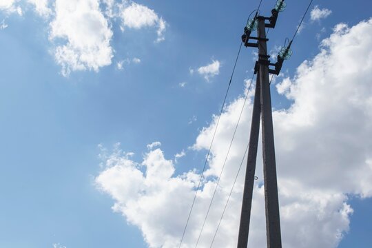 Energy, electricity transmission tower. Power transmission pole with power lines and insulators on a background of blue sky with clouds.