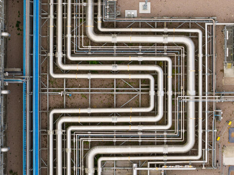 Aerial view of industrial metal piping system with complex geometric patterns and steel support structures at a facility in the United Kingdom.