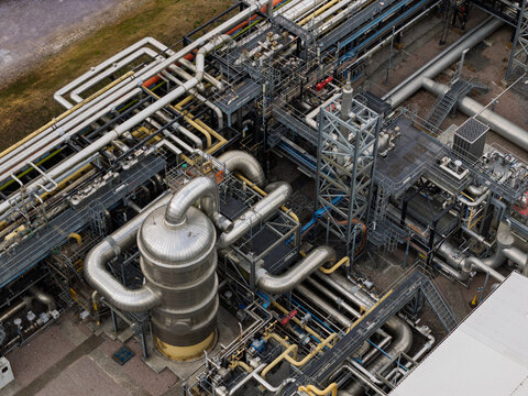 Aerial view of an industrial chemical processing plant featuring complex networks of metal pipes, large storage tanks, and steel support structures in the United Kingdom.