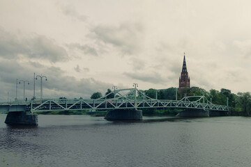 Fototapeta premium Pori Finland iconic bridge over Kokemaenjoki River with Central Pori Church steeple under cloudy sky