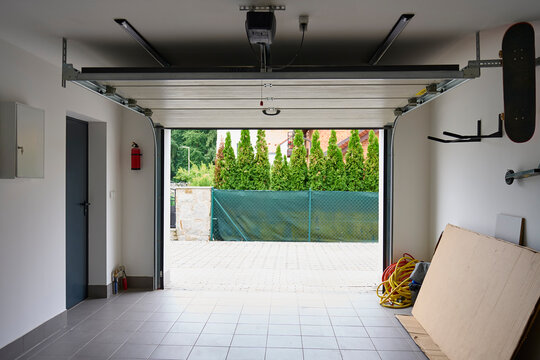 Open sectional garage door with automatic opener inside residential garage