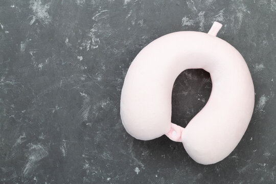 Pink travel pillow on concrete background, top view
