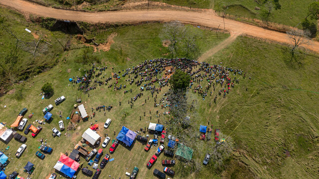 Aerial view of Rally Paraguay with spectators gathered on a grassy hillside, parked vehicles, and tents near a dirt road in Nueva Alborada, Itapua Department, Paraguay.