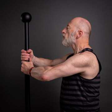 head and shoulder portrait of senior man exercising with a steel mace,  fitness over 60 concept