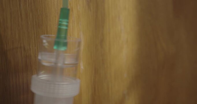 Close-up of an oxygen breathing mask hanging from a bedside cabinet in a cinematic home setting, suggesting respiratory treatment and medical care.