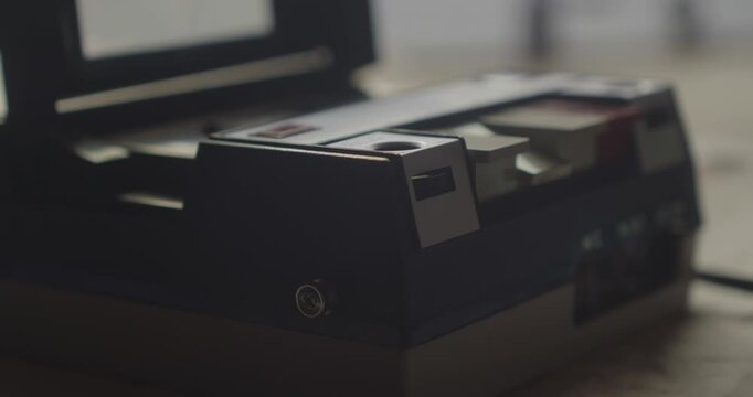 Close-up side profile shows a finger activating the record button on a retro cassette player, illustrating hands-on analog audio recording technology.