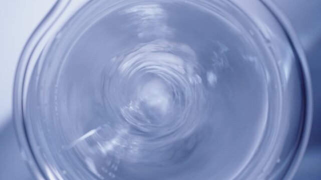 Liquid mixing chemical reagent vortex by magnetic stirrer in beaker, overhead zoom out