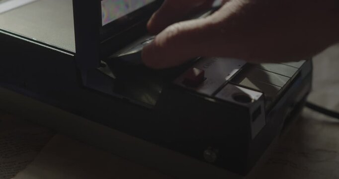 Close-up shows an audio cassette being inserted into a portable retro machine before the play button is activated for analog playback.