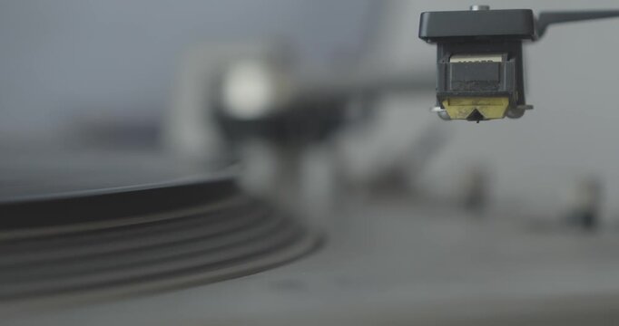 Close-up shows the automatic tonearm mechanism operating on a retro turntable as it positions the stylus to play a vinyl record.