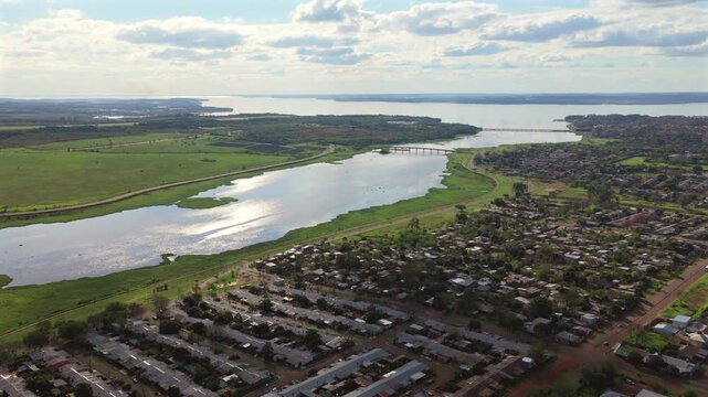 Wide aerial panorama reveals residential neighborhoods extending toward the distant skyline of Posadas, Argentina.