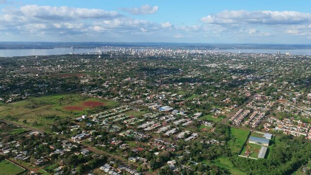 Wide cityscape reveals residential neighborhoods of Posadas extending toward the urban center and Paran&aacute; River in Misiones, Argentina.