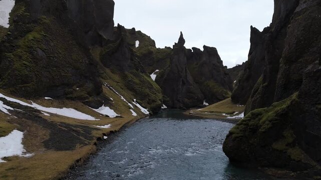 アイスランドの峡谷を流れる川をドローンで低空飛行、苔むした断崖と残雪（Iceland Canyon River Aerial 4K）
