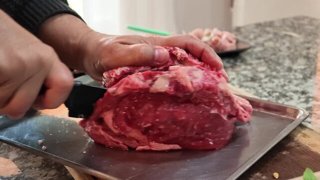 Close Up of Hands Slicing Raw Beef with a Knife for Traditional Argentine Asado