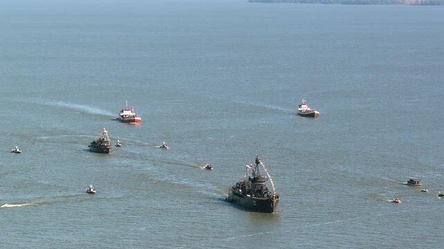 Naval vessels and tugboats move together across the Paran&aacute; River in a coordinated river navigation formation.