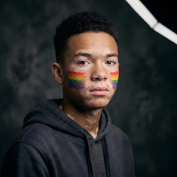 Young man with vitiligo and rainbow flag face paint pride and diversity