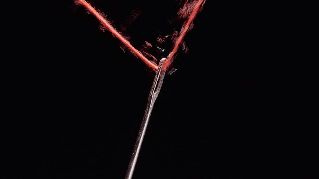 Fingers Thread Red Thread Through a Sewing Needle Against Black, Detailed Macro View of Handcraft and Care
