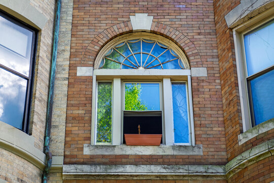 Ornate arched window with decorative glass on a brick facade in Boston
