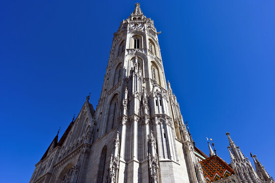 Stone bell tower closeup of the Matthias church in Budapest, Hungary. steep perspective view. religious architecture. blue summer sky. architecture, religion, travel and tourism concept