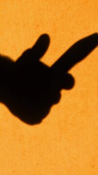 Close-up shadow silhouette of hands using a phone and scrolling