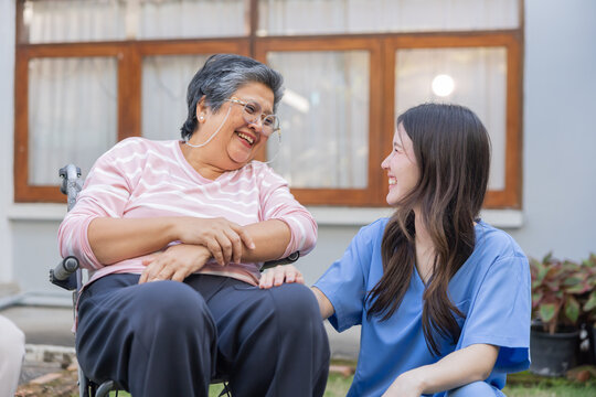 Caregiver talks with senior woman in garden during sunny afternoon