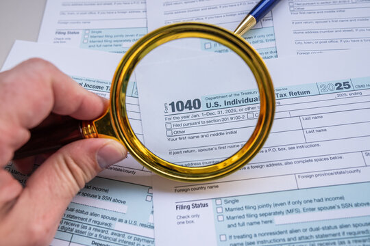 Golden Magnifying Glass on US Tax Form 1040 Papers with Pen for Detailed Audit and IRS Inspection